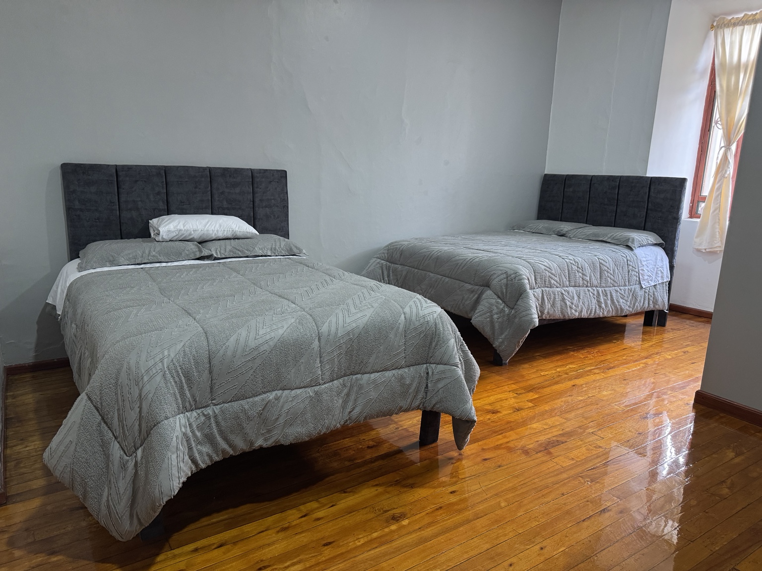 Las dos camas de la Suite 2, con pisos de madera y luz natural